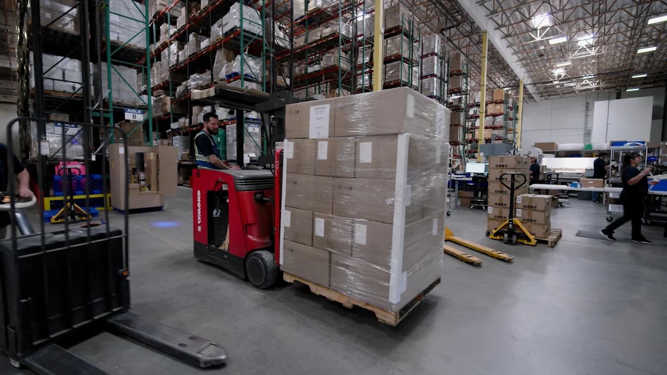Powered forklift transporting a wrapped pallet across the floor